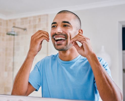 Shot of a young man flossing his teeth in the bathroom at home